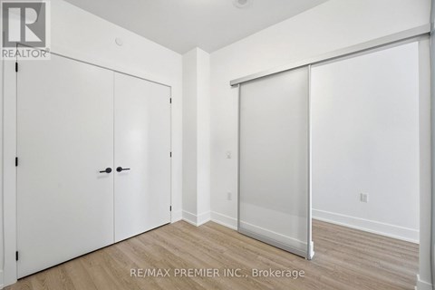 A white bedroom with a sliding door and a wooden floor.