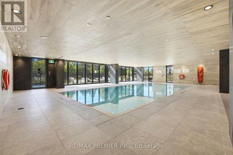 A large indoor swimming pool with a glass wall and a tiled floor.