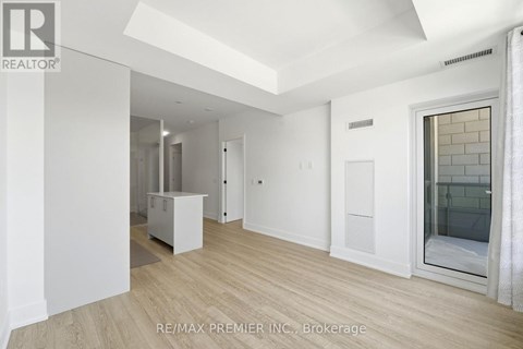 A spacious room with a white ceiling and wooden flooring.