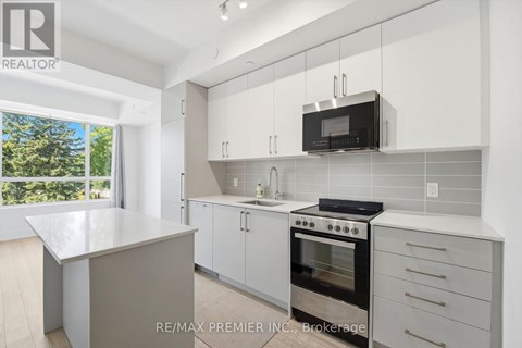 A modern kitchen with white cabinets and a microwave above the stove.