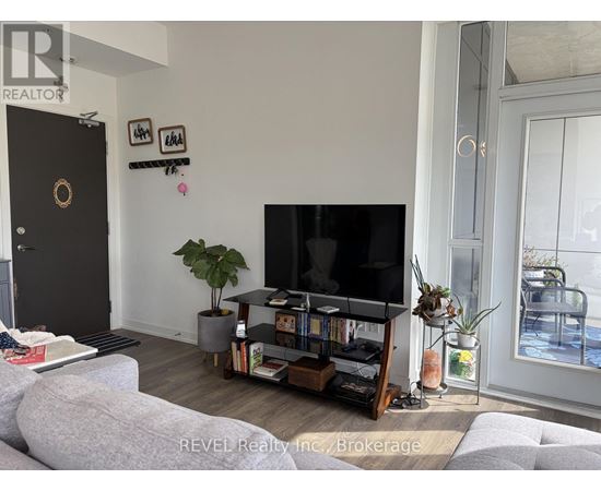 A living room with a grey couch and a black television.