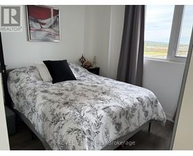 A bed with a floral patterned comforter is in a room with a window showing a view of the outdoors.