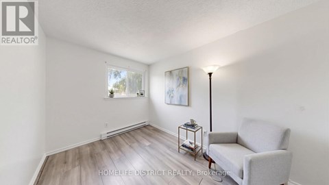 A living room with a grey sofa and a small table with a lamp on it.