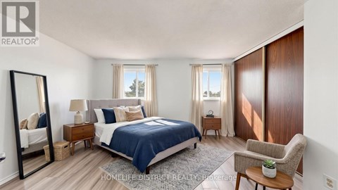 A bedroom with a bed, chair, and mirror.