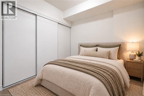 A bedroom with a bed, nightstand, and lamp.