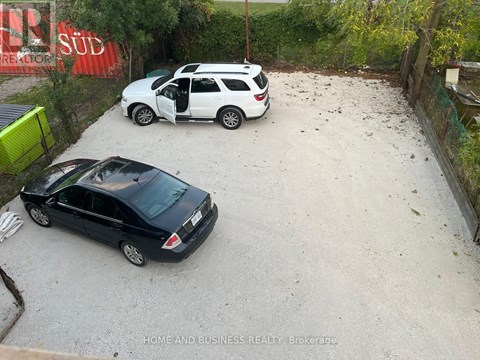 Two cars are parked in a gravel lot.