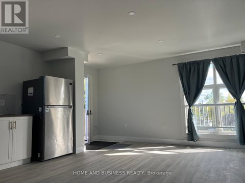 A spacious kitchen with a refrigerator and a large window with curtains.