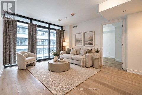 A living room with a large window, a sofa, a chair, and a coffee table.