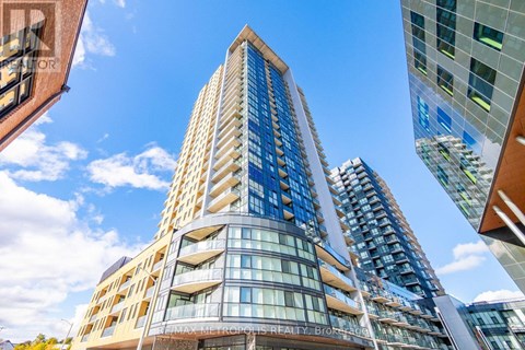 A tall building with many windows and balconies is seen from a low angle.