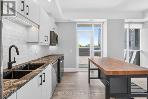 A kitchen with a wooden table and a window overlooking a green landscape.