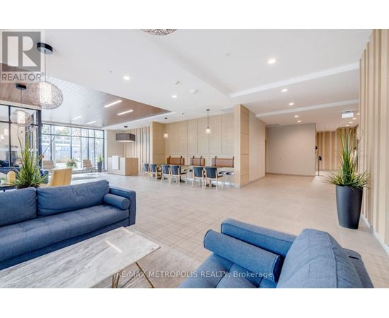 A spacious living room with a blue sofa and a dining area in the background.