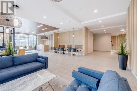 A spacious living room with a blue sofa and a dining area in the background.