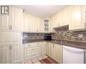 A kitchen with white cabinets and a stone backsplash.