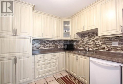 A kitchen with white cabinets and a stone backsplash.
