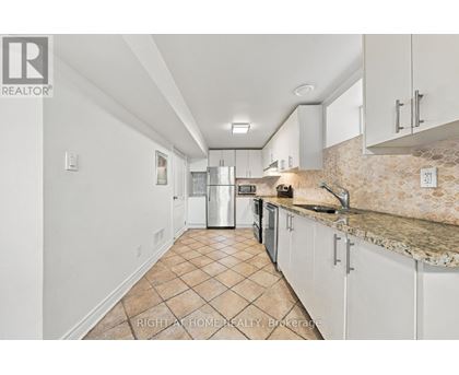 A kitchen with white cabinets and a tiled floor.