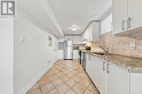 A kitchen with white cabinets and a tiled floor.