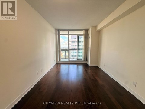 A room with wooden floors and a window overlooking a cityscape.