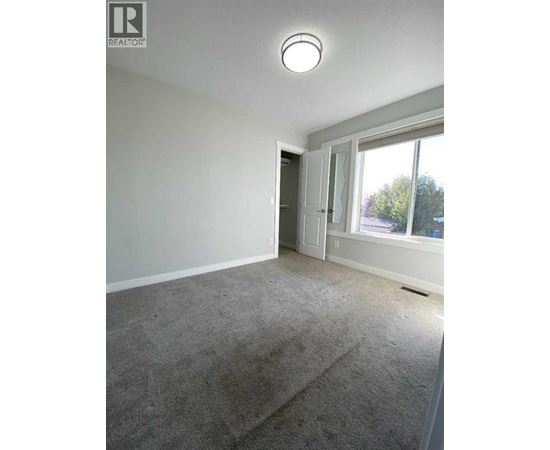 A room with a carpeted floor and a window showing a view of trees outside.