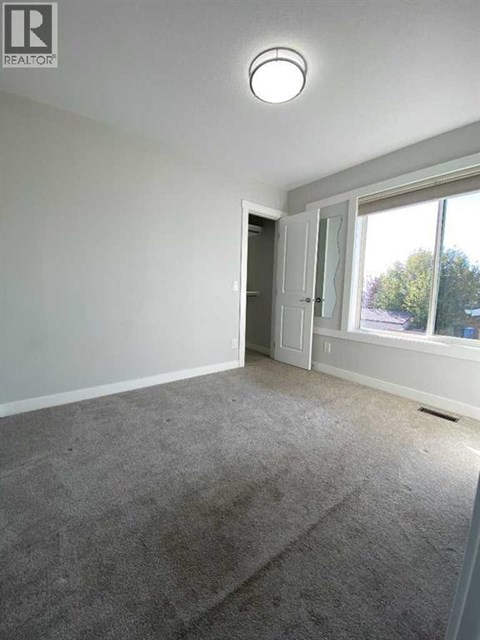 A room with a carpeted floor and a window showing a view of trees outside.