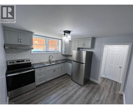 A kitchen with a stove, sink, and refrigerator.
