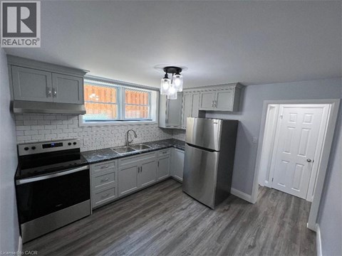 A kitchen with a stove, sink, and refrigerator.