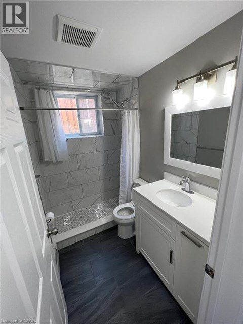 A bathroom with a toilet, sink, and shower.