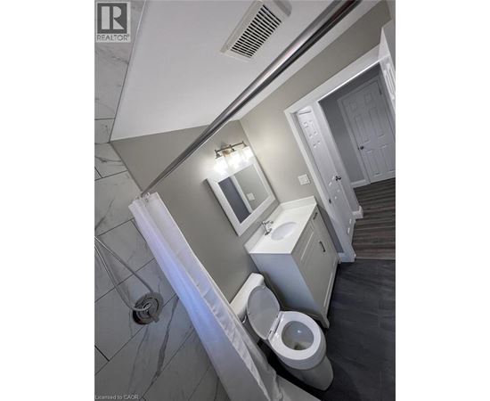 A bathroom with a toilet, sink, and mirror.