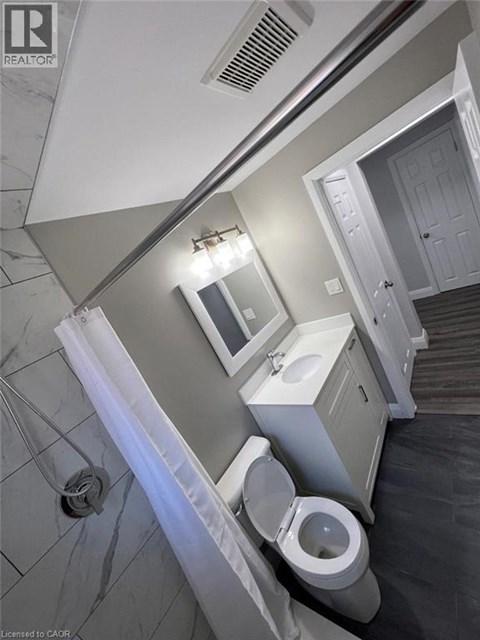 A bathroom with a toilet, sink, and mirror.