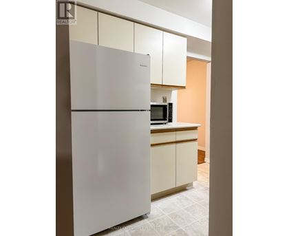 A white refrigerator in a kitchen with a microwave on the counter.