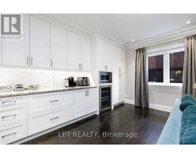 A kitchen with white cabinets and a blue couch.