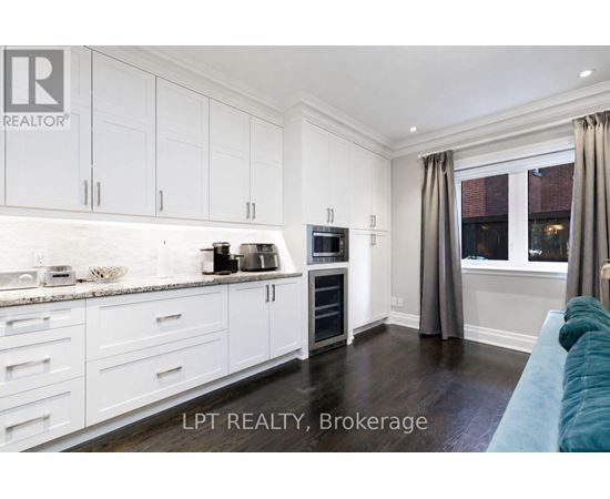A kitchen with white cabinets and a blue couch.
