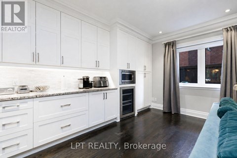 A kitchen with white cabinets and a blue couch.