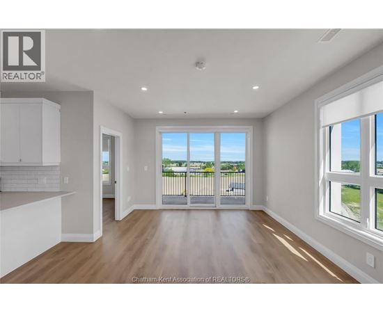 A well-lit, empty room with a view of the outdoors through a sliding glass door.