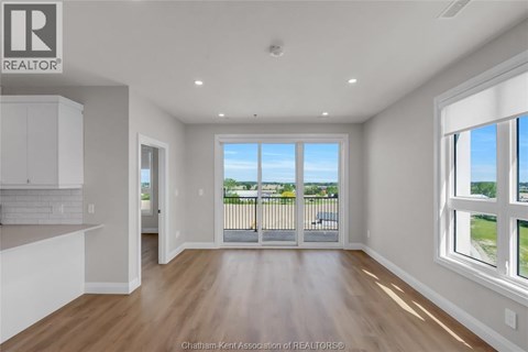 A well-lit, empty room with a view of the outdoors through a sliding glass door.