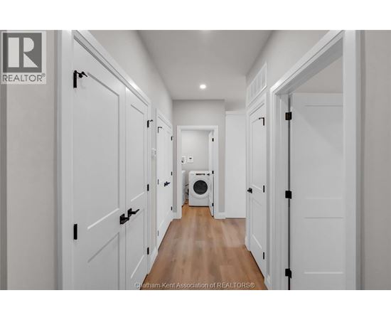 A hallway with white doors and a washing machine in the middle.