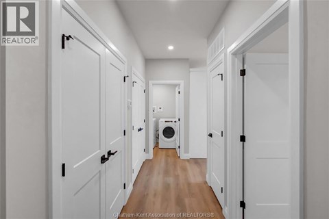 A hallway with white doors and a washing machine in the middle.