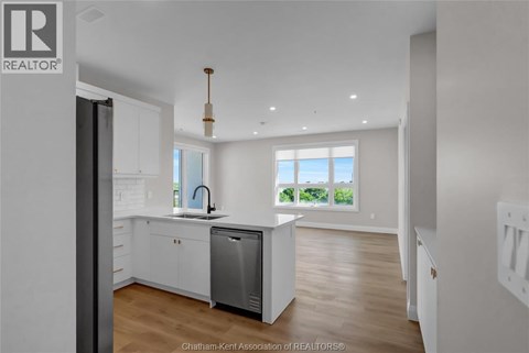 A modern kitchen with white cabinets and a large window.