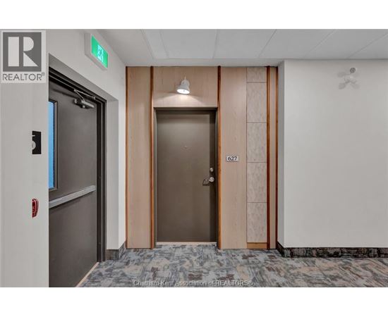 A hallway with a wooden door and a grey floor.