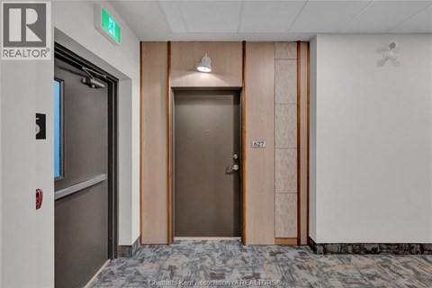 A hallway with a wooden door and a grey floor.