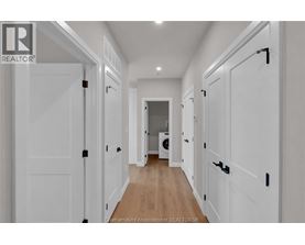 A hallway with white doors and a washing machine in the background.