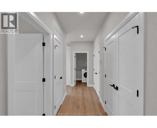 A hallway with white doors and a washing machine in the background.
