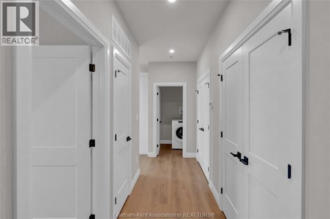 A hallway with white doors and a washing machine in the background.