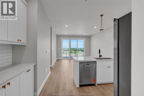 A kitchen with white cabinets and a wooden floor.