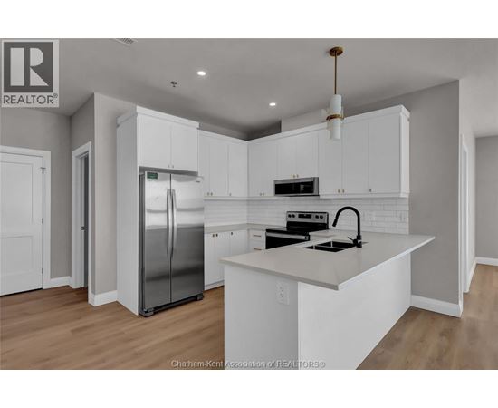 A modern kitchen with white cabinets and a stainless steel refrigerator.