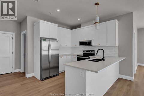 A modern kitchen with white cabinets and a stainless steel refrigerator.