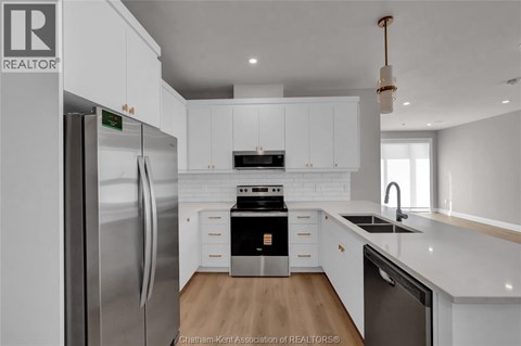 A modern kitchen with white cabinets and stainless steel appliances.