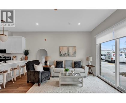 A well-lit, modern living room with a kitchen area in the background.