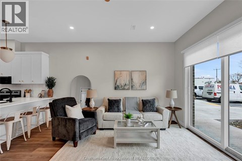 A well-lit, modern living room with a kitchen area in the background.