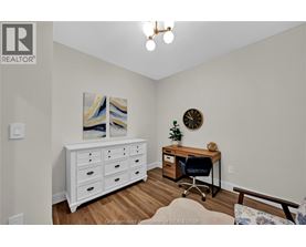 A room with a white dresser, a desk with a chair, and a painting on the wall.