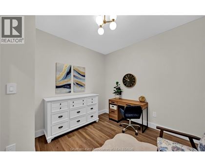 A room with a white dresser, a desk with a chair, and a painting on the wall.